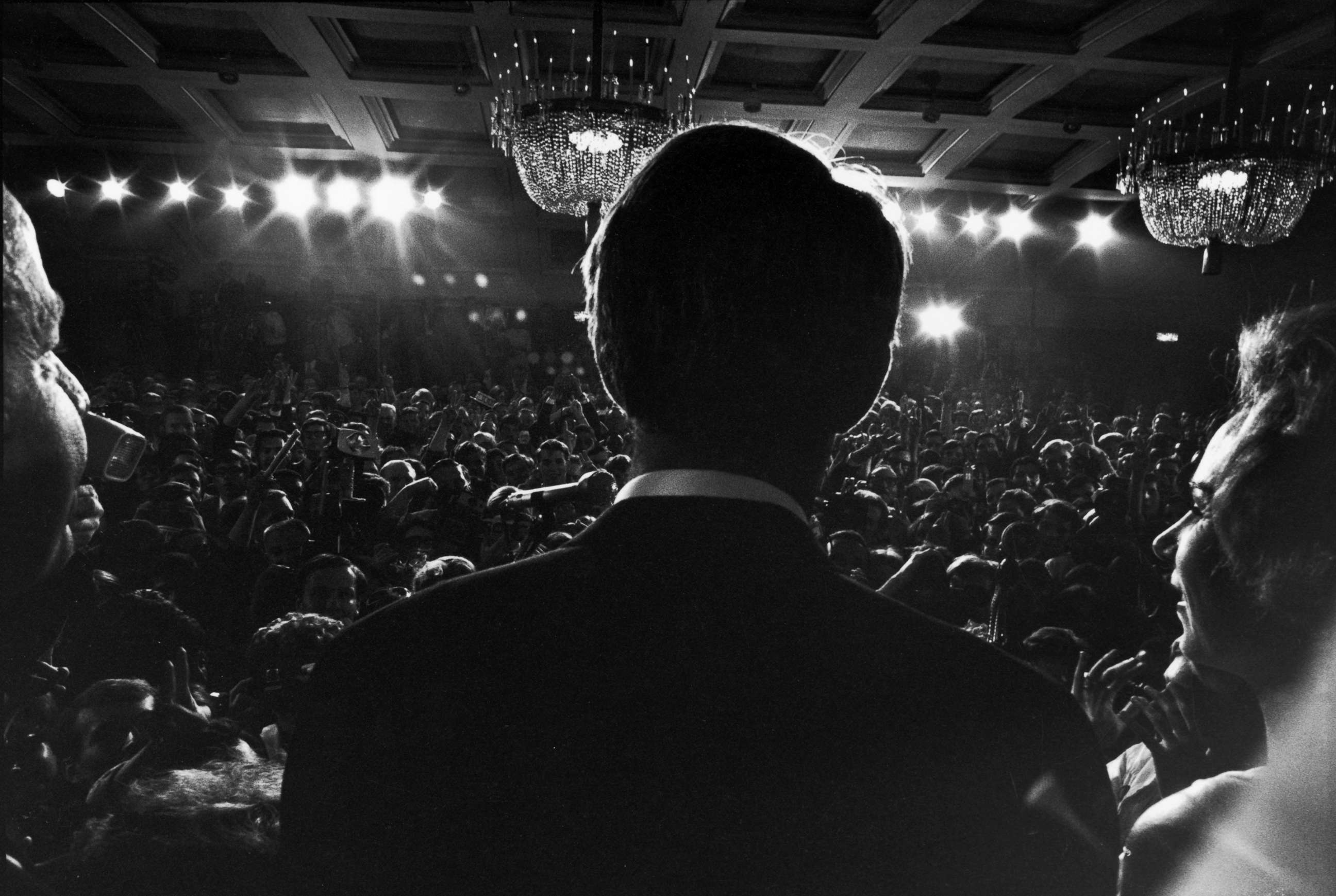 PHOTO: Rear view of Sen. Robert Kennedy and his pregnant wife Ethel standing at a podium at the Ambassador Hotel as he addresses supporters  after his California primary election victory, Los Angeles, June 5, 1968.