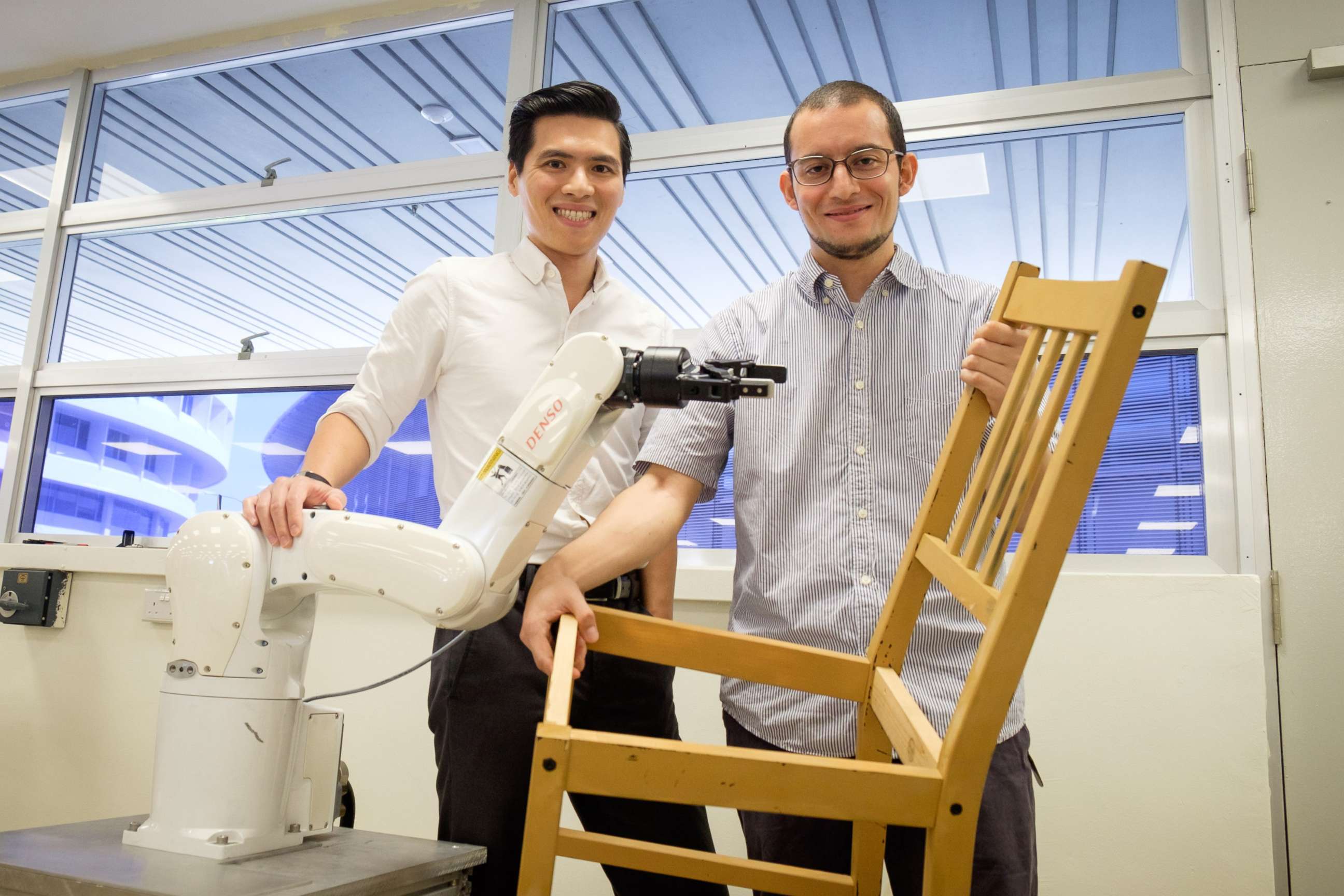 PHOTO: A photo released on April 19, 2018 by Nanyang Technological University shows assistant professor Pham Quang Cuong and research fellow Francisco Suarez-Ruiz posing with an autonomous robotic arm capable of assembling IKEA furniture, in Singapore.