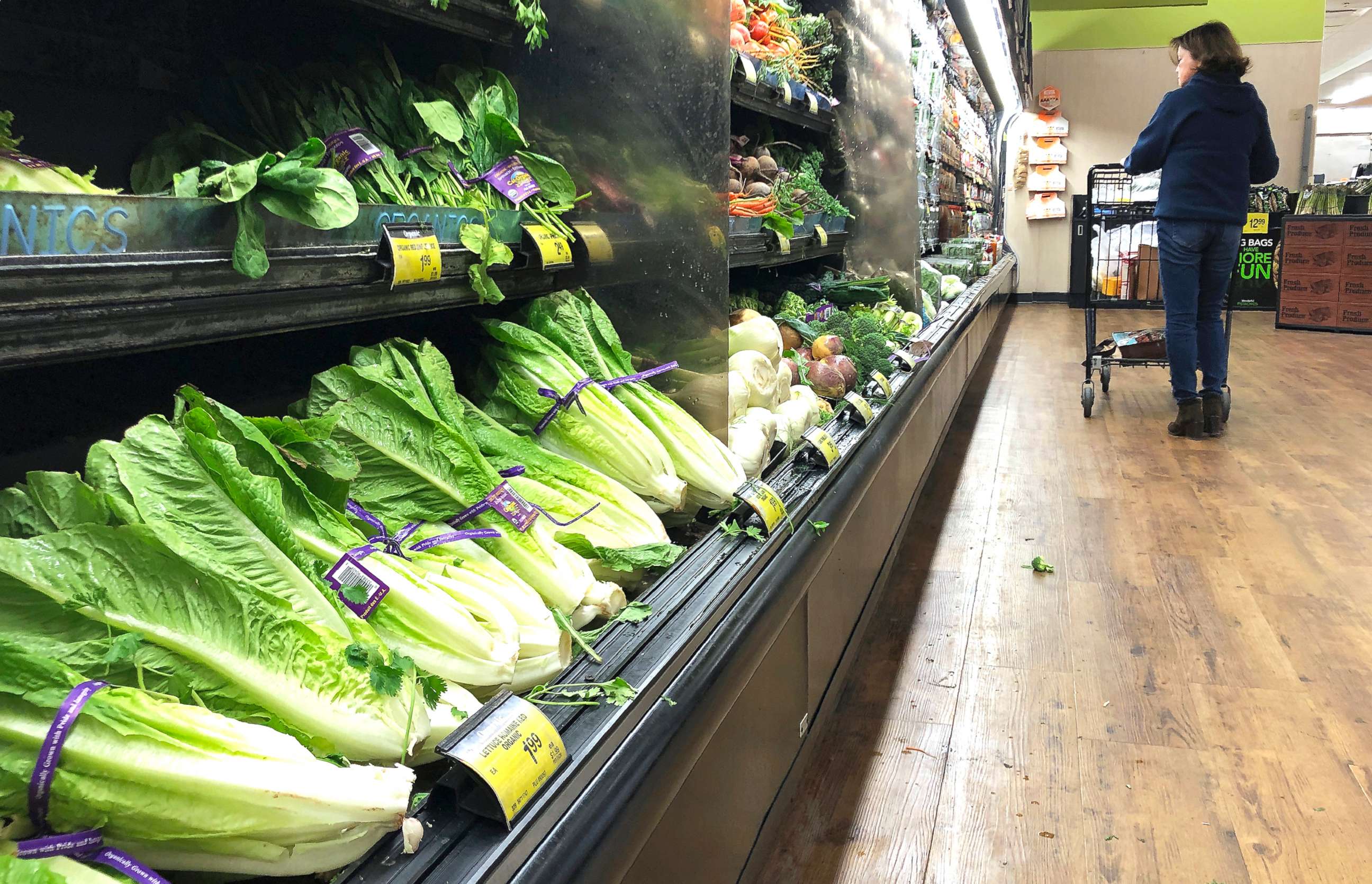 PHOTO: In this Nov. 20, 2018, file photo, romaine lettuce sits on the shelves as a shopper walks through the produce area of an Albertsons market in Simi Valley, Calif.