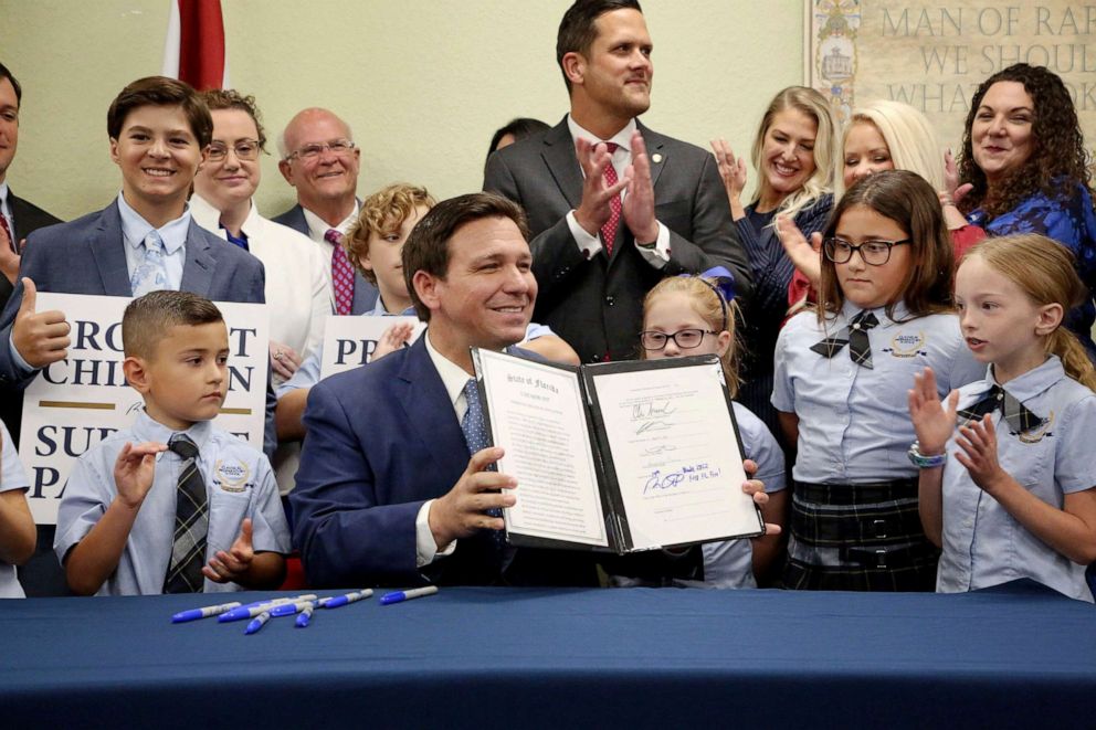 PHOTO: Florida Gov. Ron DeSantis displays the signed Parental Rights in Education, aka the Don't Say Gay bill, flanked by elementary school students during a news conferencey, March 28, 2022, at Classical Preparatory school in Shady Hills.