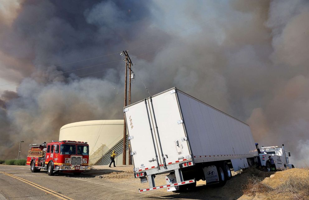 PHOTO: Firefighters work as a tow truck prepares to move the trailer of a truck while the Route Fire burns nearby, Aug. 31, 2022, near Castaic, Calif.