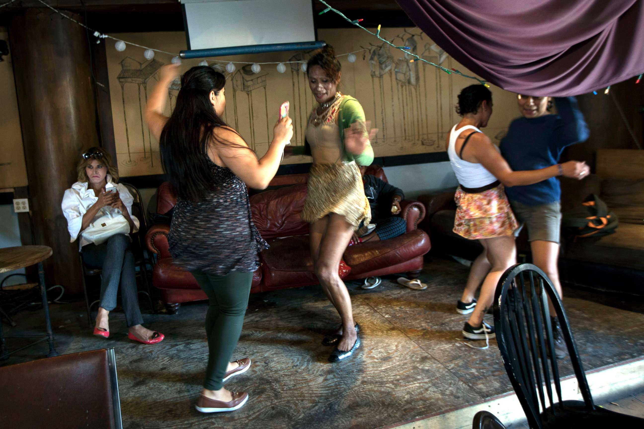PHOTO: In this undated 2018 photo, Roxana Hernandez, sitting at left, checks her cell phone while her friends dance at the community center called El Caracol, where legal aid was being offered to migrants by volunteer US Lawyers, in Tijuana, Mexico.