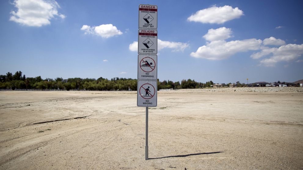 PHOTO: Signs warning of underwater hazards stand over a portion of dried up lake bed at Lake Elsinore in Lake Elsinore, Calif., July 23, 2015.