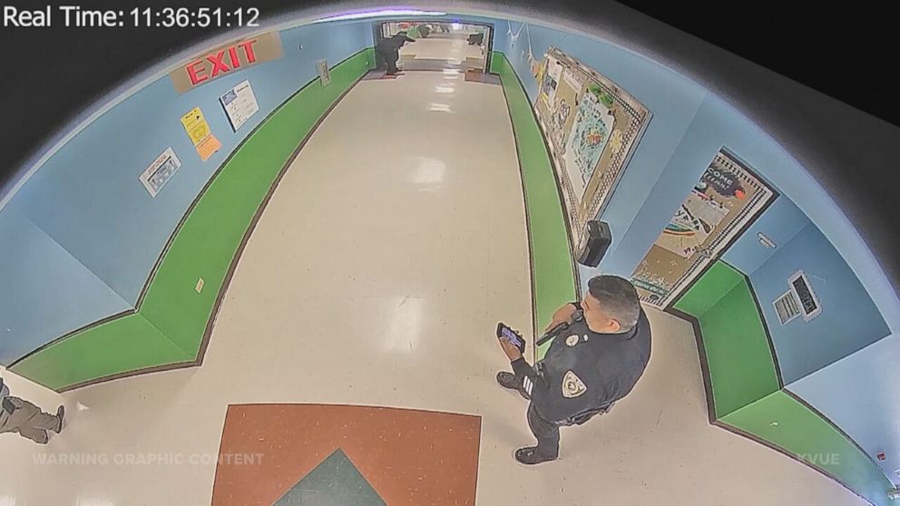 PHOTO: Officer Ruben Ruiz checks his phone during in the hallway of Robb Elementary School on May 24, 2022. Authorities said Ruiz had been texting with his wife, Eva, as she was trapped in the classroom, wounded and dying.