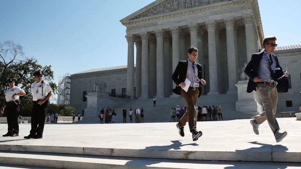 PHOTO: Two CBS interns run with a newly released Supreme Court ruling June 20, 2016 in Washington. 