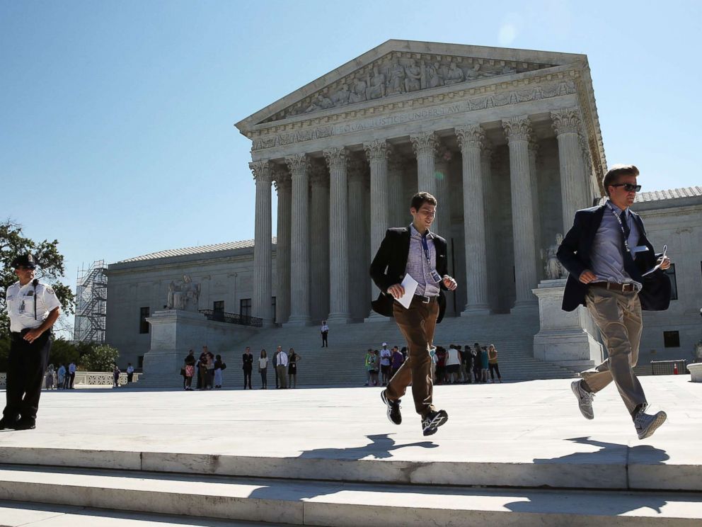 PHOTO: Two CBS interns run with a newly released Supreme Court ruling June 20, 2016 in Washington.