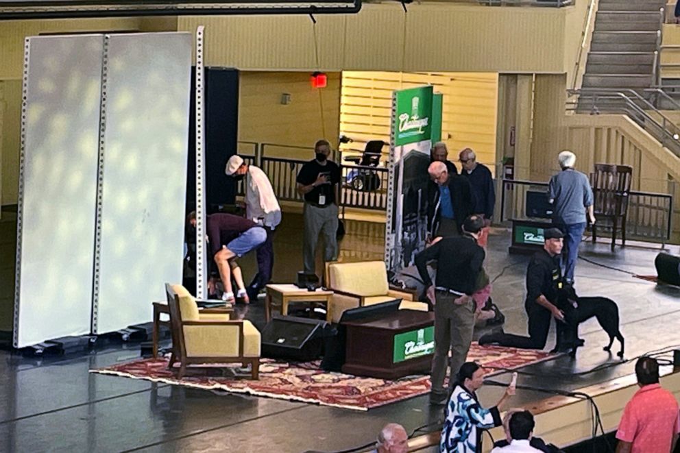 PHOTO: Author Salman Rushdie, behind screen left, is tended to after he was attacked during a lecture, Aug. 12, 2022, at the Chautauqua Institution in Chautauqua, N.Y.