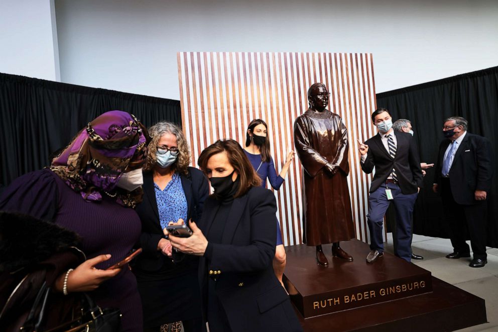 PHOTO: People pose for a photo next to the statue of the late US Supreme Court Justice Ruth Bader Ginsburg at City Point, Brooklyn, on March 12, 2021, in New York.