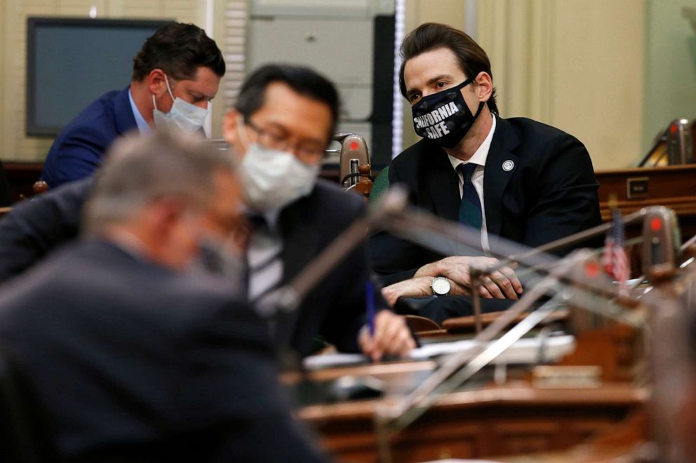 PHOTO: Wearing a face mask reading "California safe," Assemblyman Kevin Kiley, right, attends a hearing of the Assembly Transportation Committee in Sacramento, Calif., May 4, 2020.