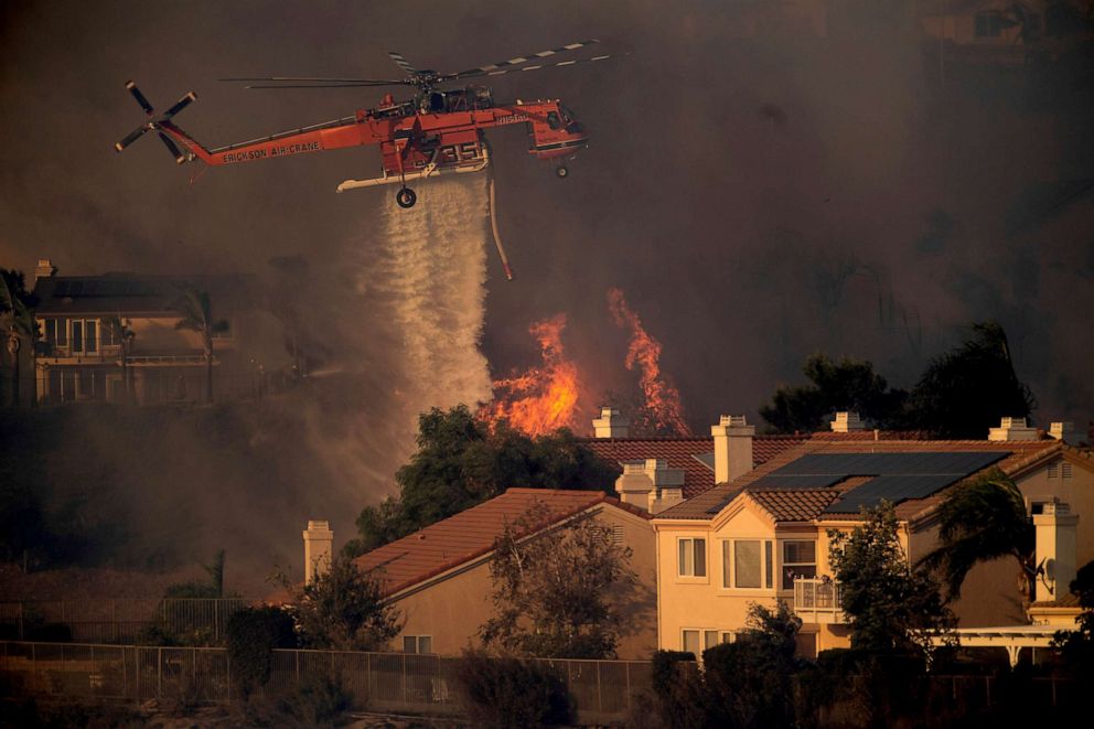 PHOTO: A helicopter drops water while battling a wildfire called the Saddle Ridge Fire in Porter Ranch, Calif. on Oct. 11, 2019.