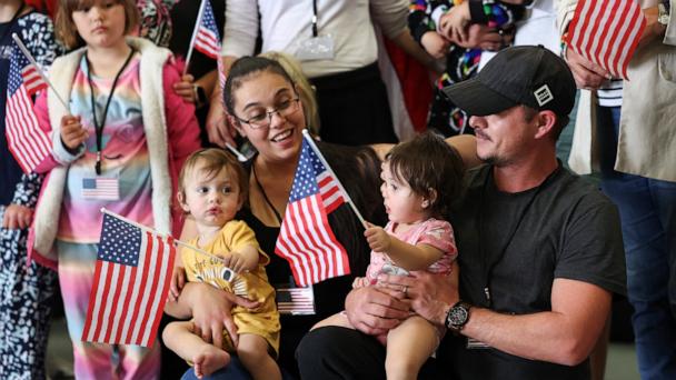 Some of the first group of white South Africans granted refugee status hold U.S. flags as they attend a meet and greet event, at Dulles International Airport, in Dulles, Virginia, May 12, 2025. 