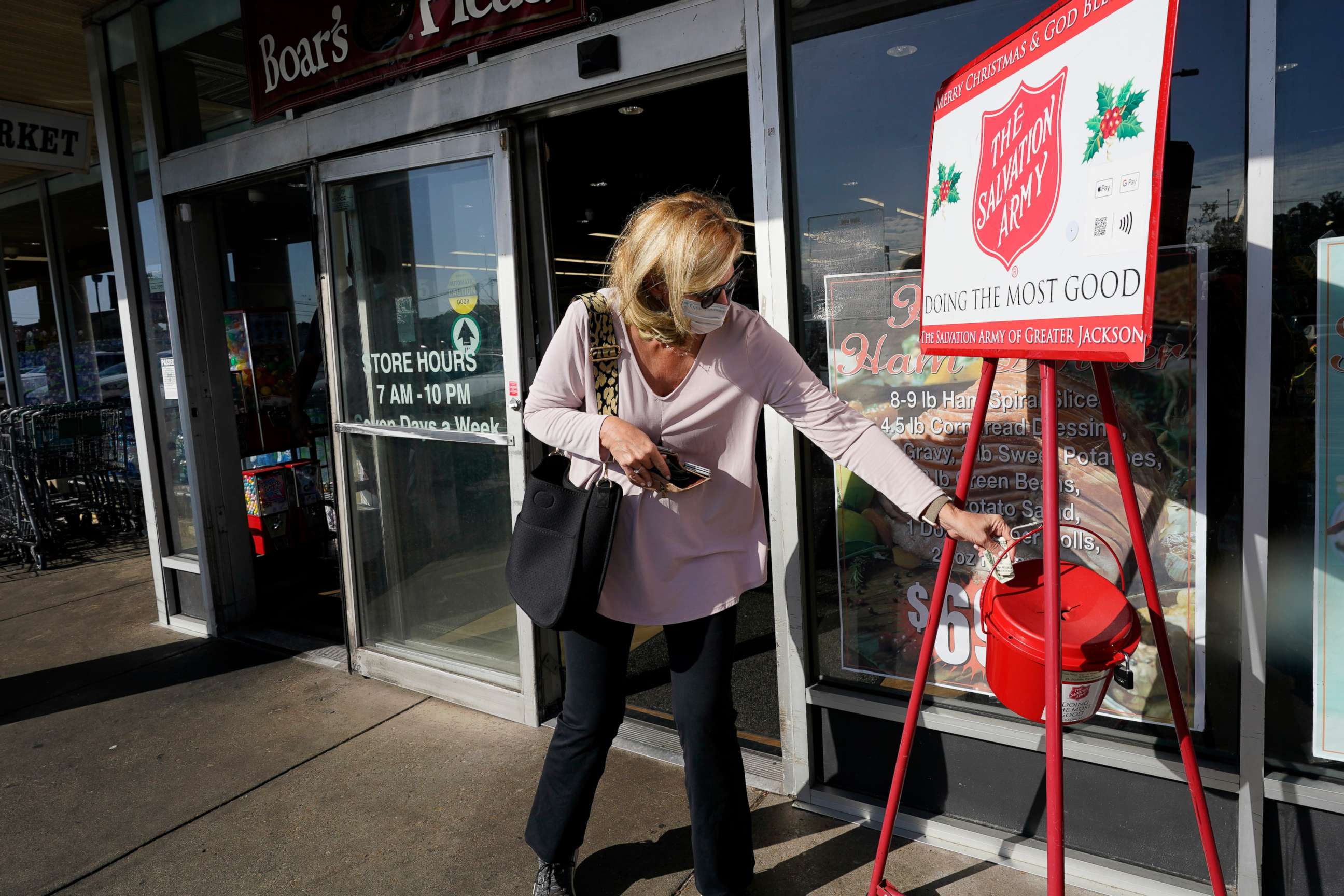 PHOTO: A Corner Market grocery store customer places money in the iconic Salvation Army donations collections bucket in Jackson, Miss., Wednesday, Nov. 25, 2020.