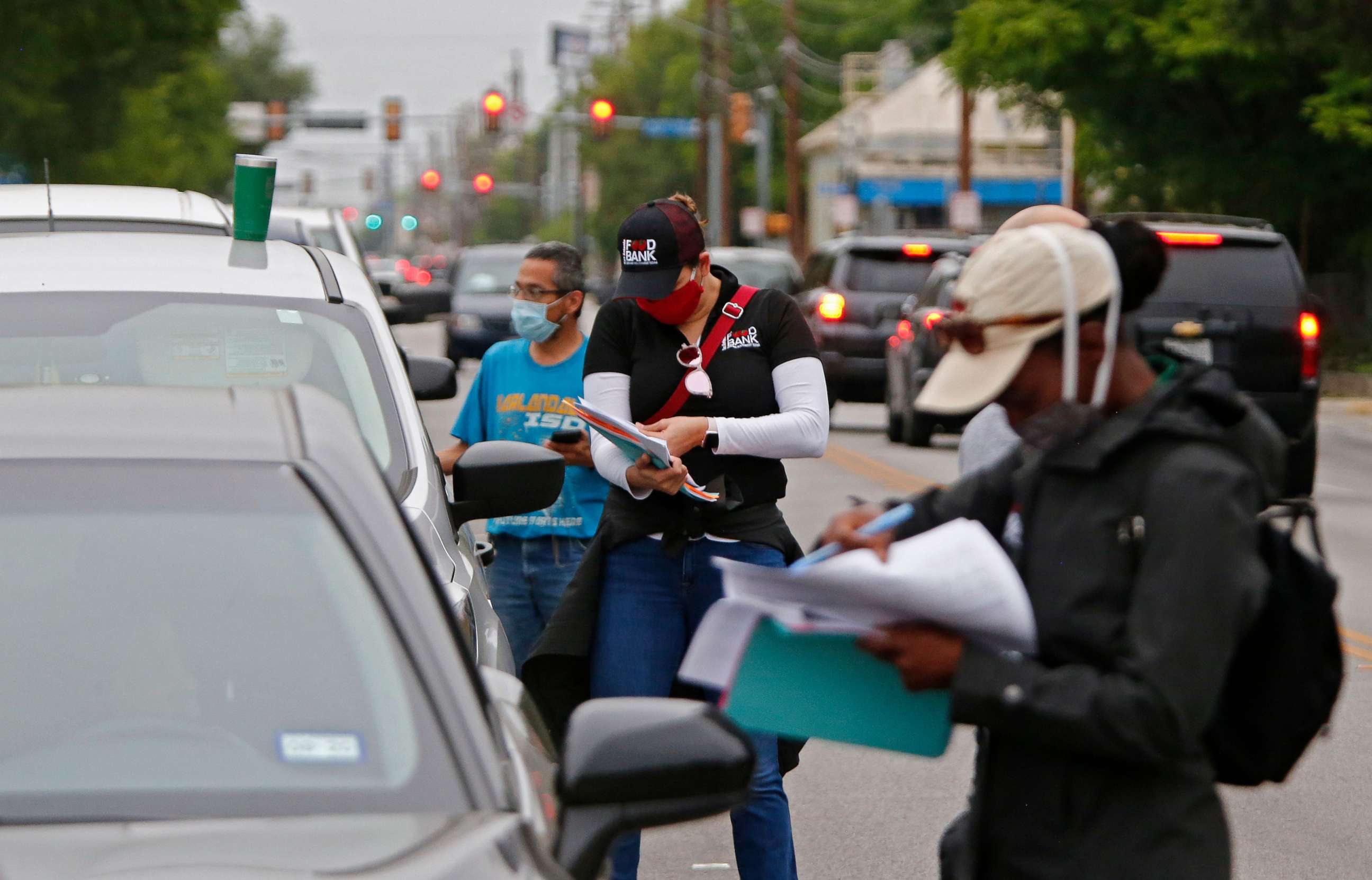 PHOTO: People waiting in line to get food at the San Antonio Food Bank distribution center being held in the parking lot at the Alamo Dome in San Antonio, April 17, 2020, are checked. 