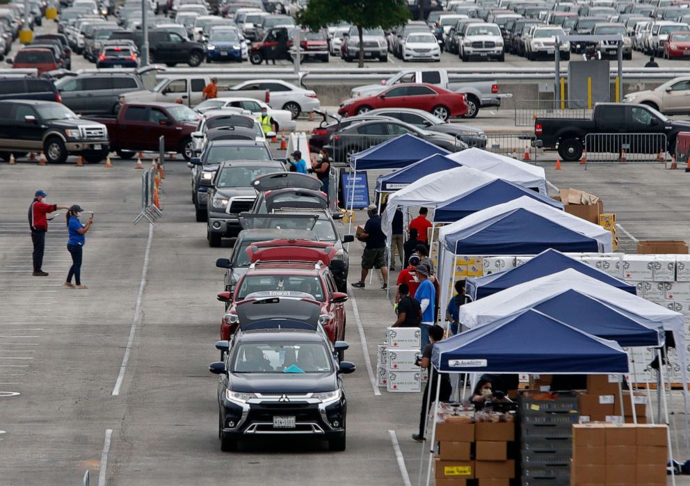 PHOTO: People wait in line to get food at the San Antonio Food Bank distribution center being held in the parking lot at the Alamo Dome in San Antonio, April 17, 2020. 