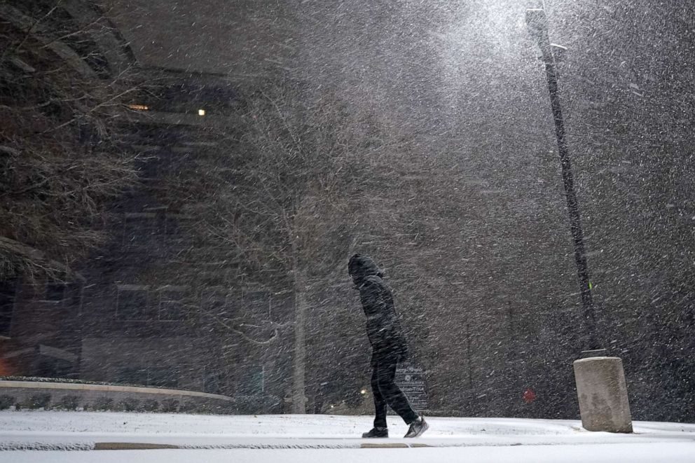 PHOTO: A woman walks through falling snow in San Antonio, Feb. 14, 2021. Snow and ice blanketed large swaths of the U.S., prompting canceled flights, making driving perilous and reaching into areas as far south as Texas's Gulf Coast. 