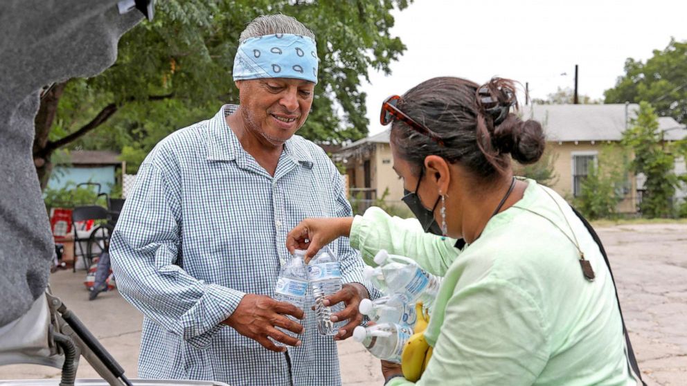 PHOTO: Susana Segura, with Bread and Blankets Mutual Aid, gives out water, bananas and hats to ward off the sun to unhoused people and others in need during a heat advisory in San Antonio, Texas, July 21, 2022.
