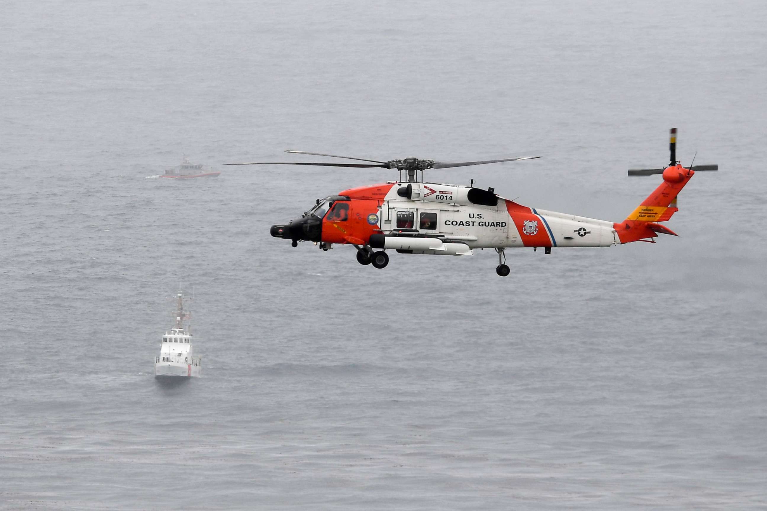 PHOTO: A U.S. Coast Guard helicopter flies over boats searching the area where a boat capsized just off the San Diego coast, May 2, 2021, in San Diego.