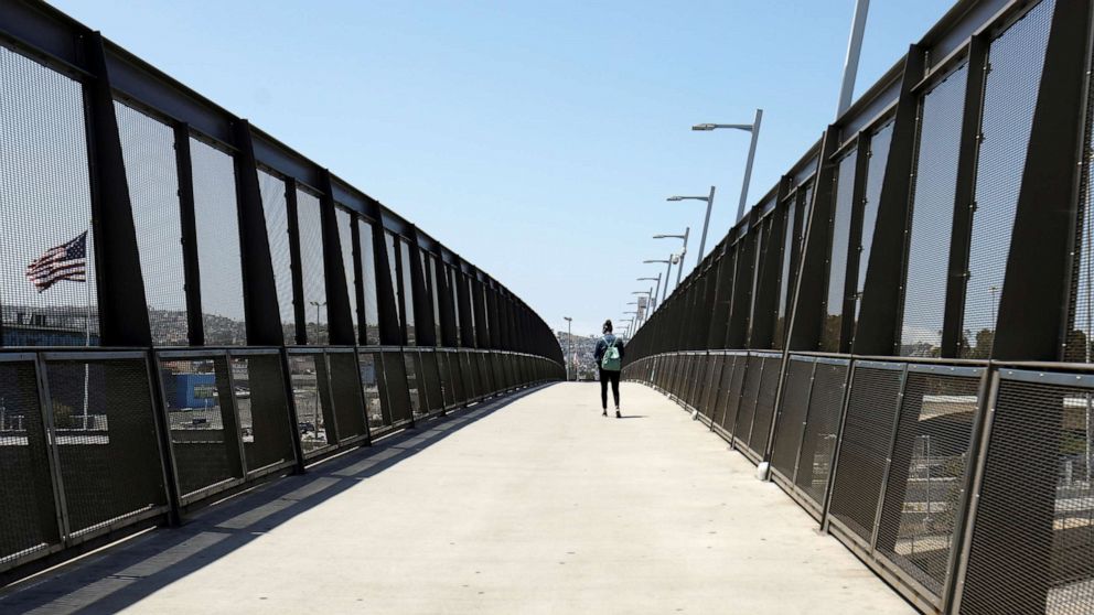 PHOTO: A lone pedestrian walks across the pedestrian bridge at the U.S.-Mexico border during the coronavirus disease (COVID-19) outbreak in San Diego, April 21, 2020.