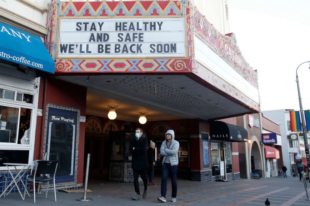 PHOTO: A man wears a mask while walking under the marquee of The Castro Theatre in San Francisco, March 16, 2020. 