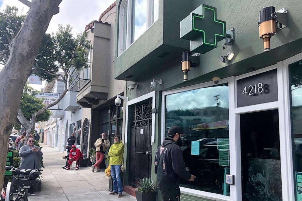 PHOTO: Customers maintain social distance while waiting to enter The Green Cross cannabis dispensary in San Francisco, March 18, 2020.