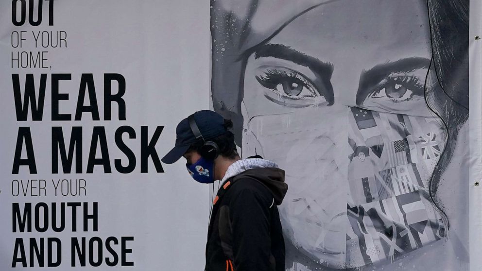 PHOTO: In this Saturday, Nov. 21, 2020, file photo, a pedestrian walks past a mural reading: "When out of your home, Wear a mask over your mouth and nose," during the coronavirus outbreak in San Francisco.
