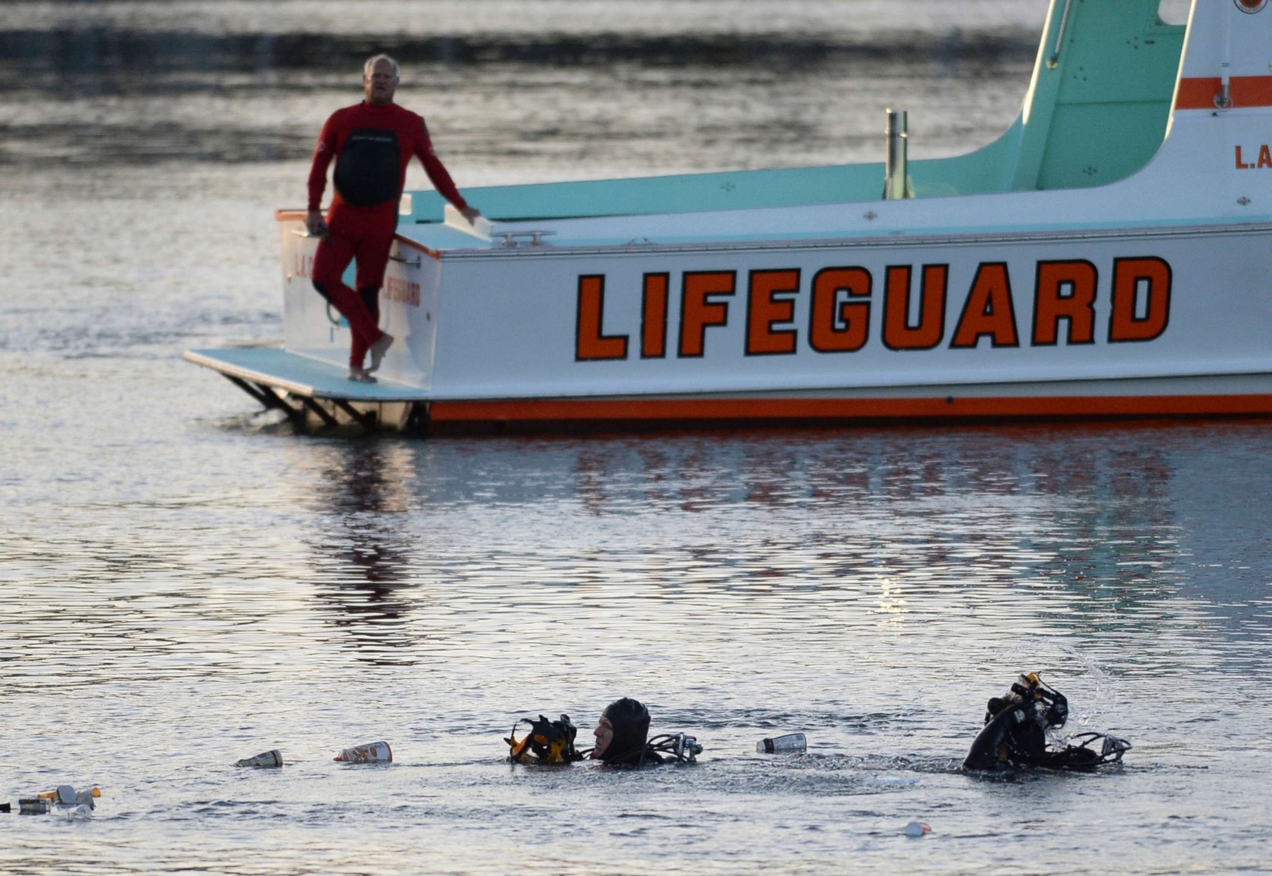 PHOTO: Divers emerge from the water as debris believed to be from a car floats to the surface, where a car went off a pier and into the water, in Los Angeles' San Pedro harbor district, April 9, 2015.