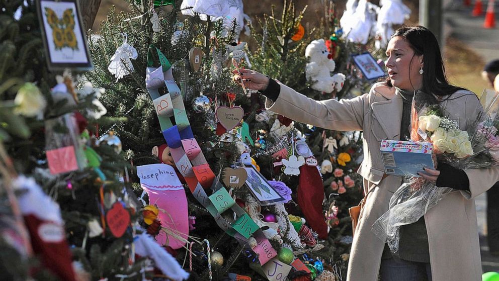 PHOTO: A woman hangs candy canes on the 26 trees near a memorial for the victims of the Sandy Hook Elementary School shooting on Dec. 20, 2012, in Newtown, Conn.