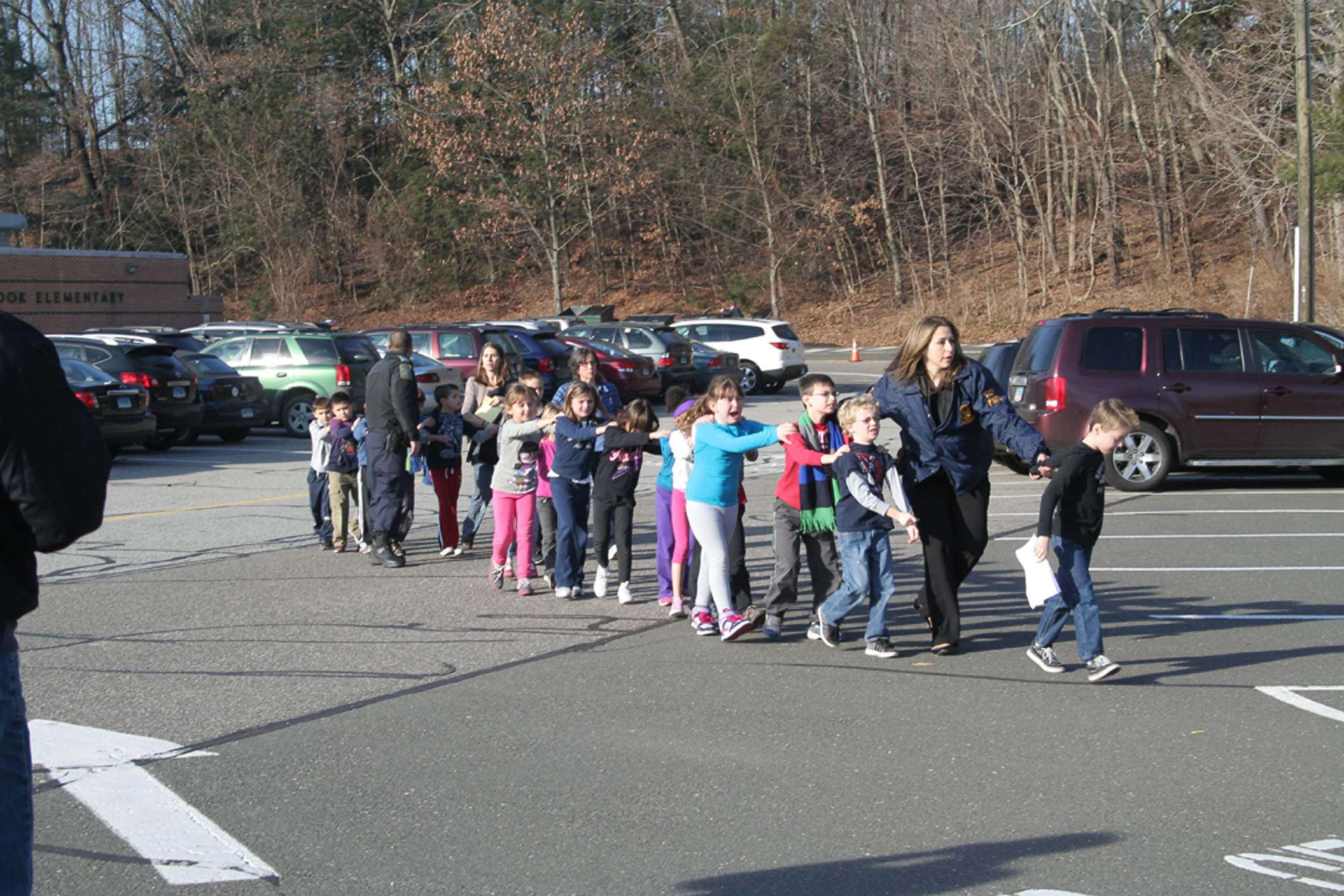 Two Connecticut State Police officers escort a class of students and two adults out of Sandy Hook Elementary School in Newtown, Conn., Dec. 14, 2012, after a shooter entered the building and killed 20 children and six adults before taking his own life.