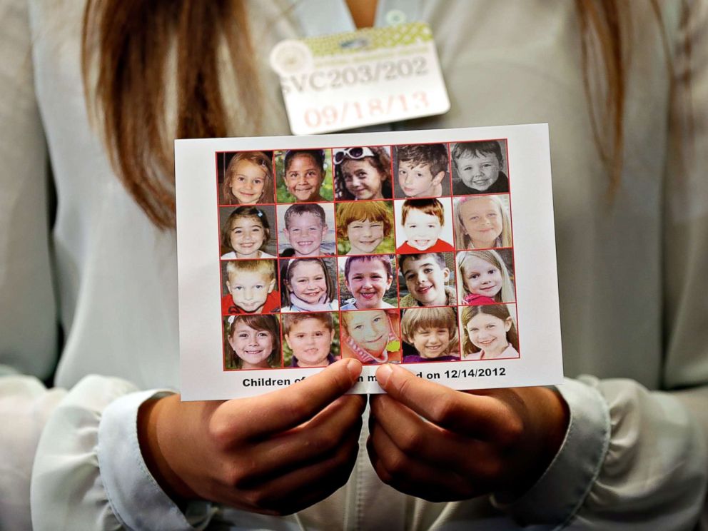 FOTO: Kyra Murray detém uma foto mostrando as vítimas do tiroteio na Escola Primária de Sandy Hook durante uma conferência de imprensa no Capitólio dos EUA pedindo legislação em reforma de armas, 18 de setembro de 2013, em Washington, DC.