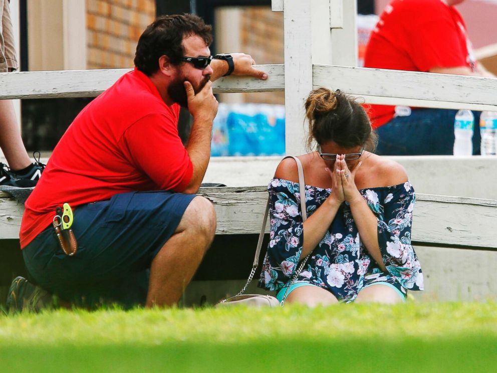 PHOTO: A woman prays in the grass outside the Alamo Gym where parents wait to reunite with their kids following a shooting at Santa Fe High School, May 18, 2018, in Santa Fe, Texas.