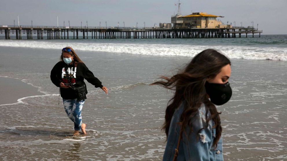 PHOTO: Malia Pena, foreground, and her mother, Lisa Torriente, wear masks as they visit the beach, June 23, 2020, in Santa Monica, Calif.