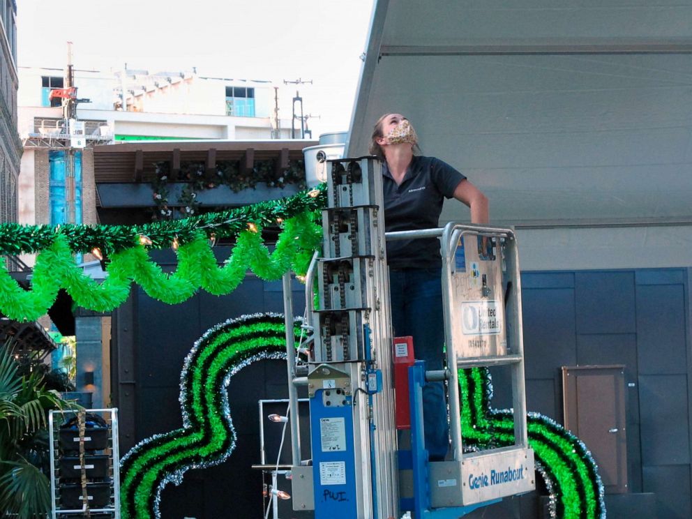 PHOTO: Sarah Hardilek uses a mechanical lift to hang green streamers for St. Patrick's Day at the Plant Riverside hotel and entertainment complex in Savannah, Ga., March 11, 2021.