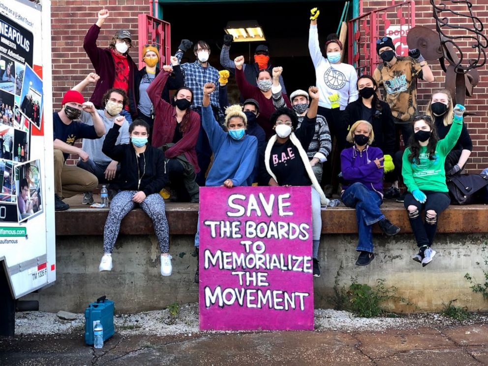 PHOTO: Kenda Zellner-Smith, center left, and Leesa Kelly, center right, pose with a group of activists. Protest art has been collected by Save the Boards to Memorialize the Movement.