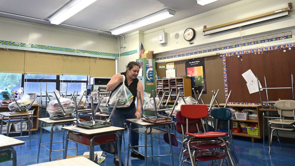 PHOTO: Holly DeMitry-Dolan, a teacher at Yung Wing School P.S. 124, moves desks and chairs in her classroom to socially distance desks for the 2020/2121 school year, Aug. 17, 2020 in New York.