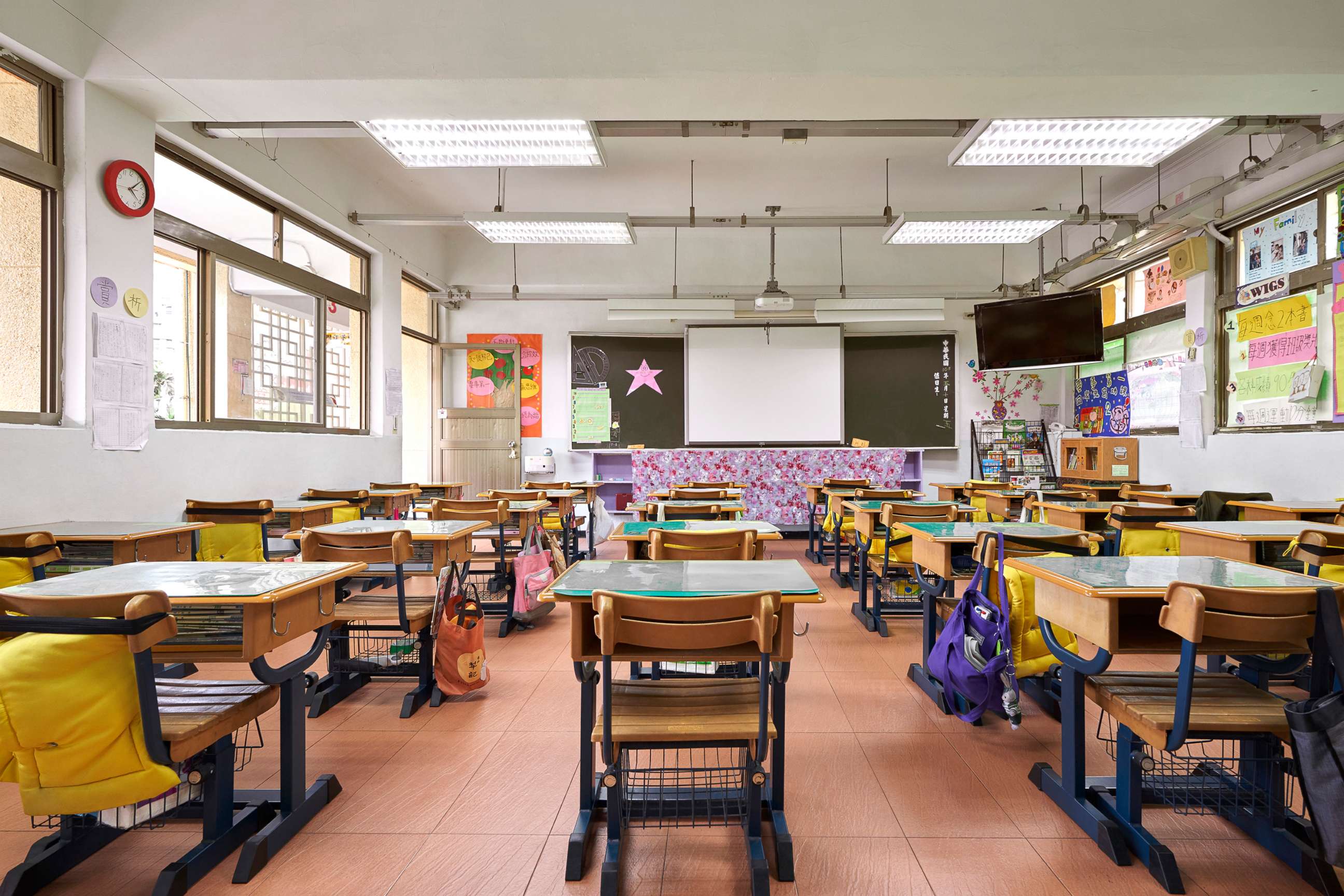 PHOTO: Interior of classroom in elementary school. Row of empty desks are in illuminated room.