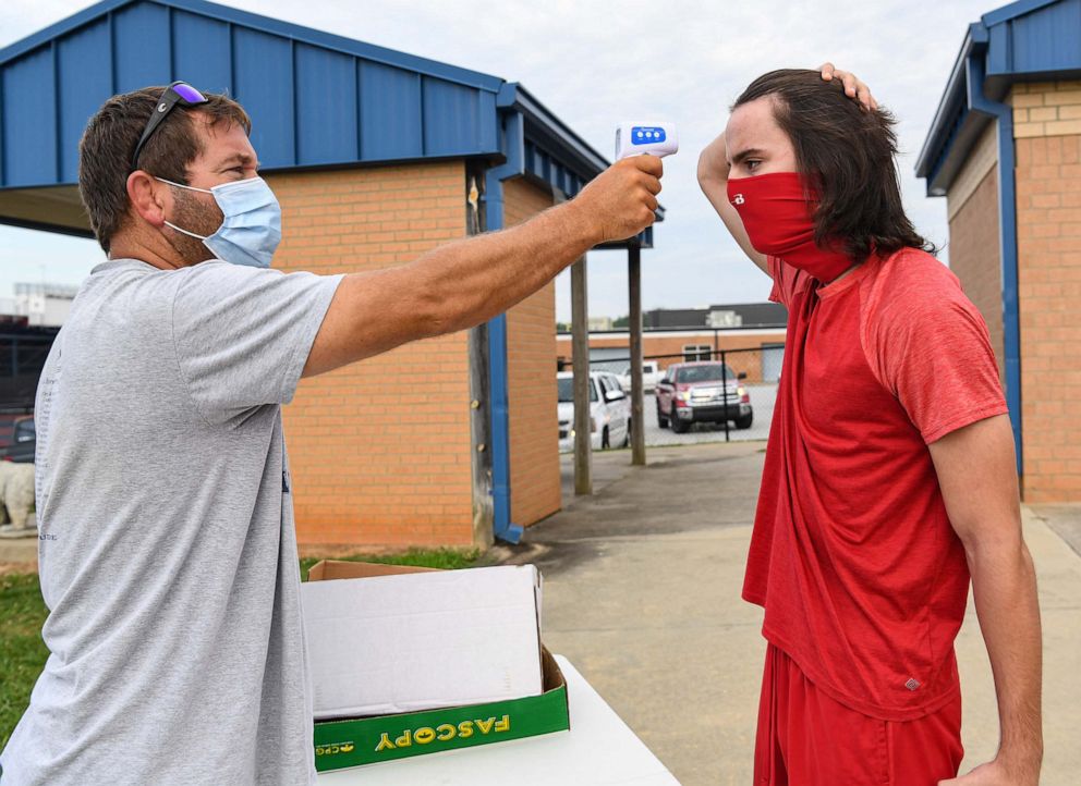 PHOTO: Assistant coach Chris Strickland checks the temperature of linebacker Anthony Brantly before a summer football workout at Belton-Honea Path High School in Honea Path, S.C., July 20, 2020.