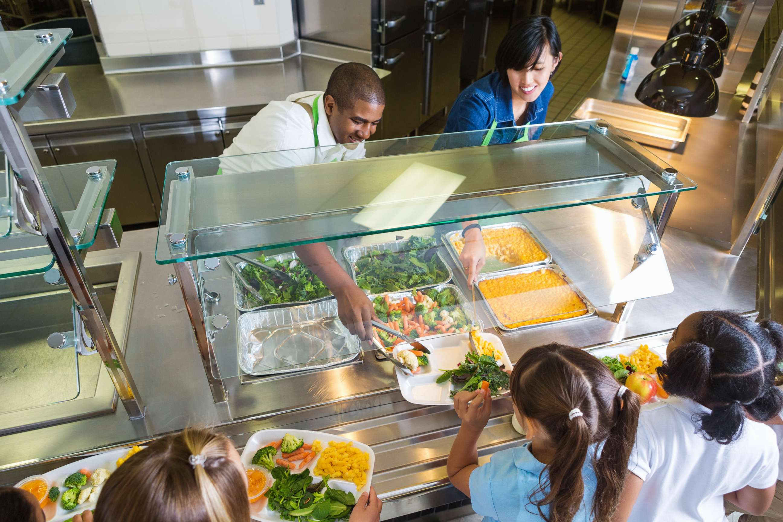 PHOTO: Cafeteria workers serving food to school children.