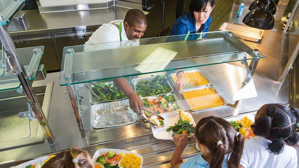 PHOTO: Cafeteria workers serving food to school children.