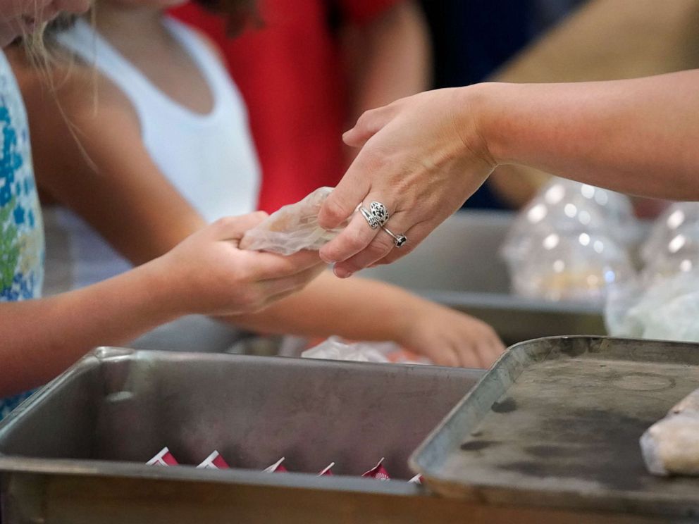 PHOTO: A food services worker hands a sandwich to a student while serving lunch at a school in Buxton, Maine, July 12, 2018.