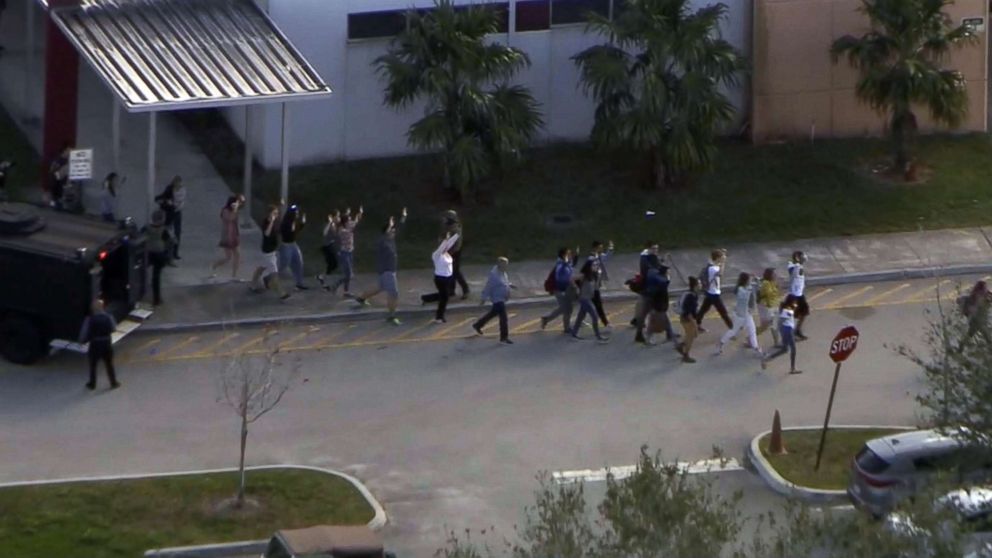 PHOTO: People emerge from a building with their hands raised after reports of a shooting at Stoneman Douglas High School in Parkland, Fla., Feb. 14, 2018.