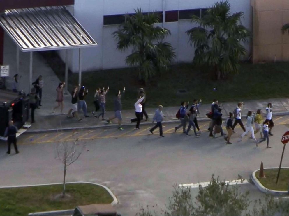 PHOTO: People emerge from a building with their hands raised after reports of a shooting at Stoneman Douglas High School in Parkland, Fla., Feb. 14, 2018.