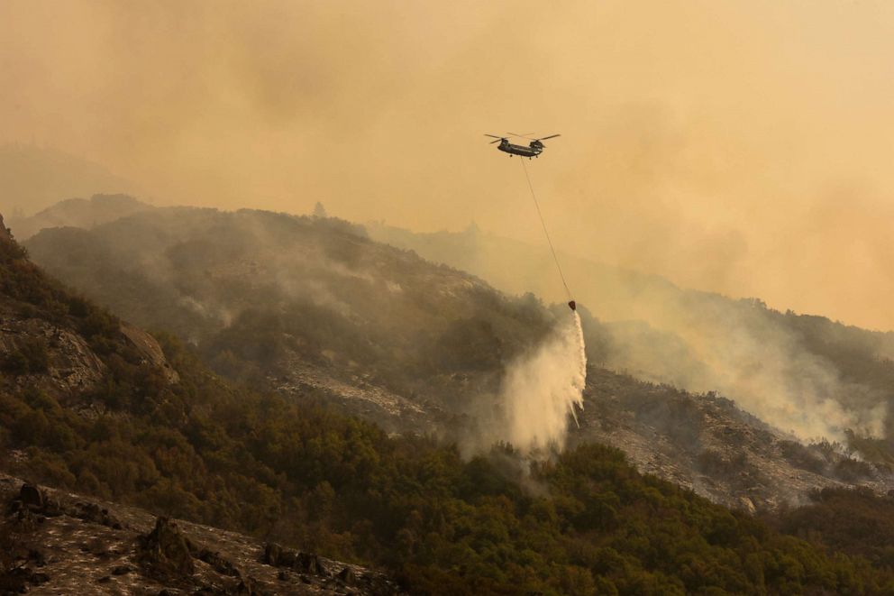 PHOTO: A Boeing CH-47 Chinook firefighting helicopter flies over smoke rising from the foothills along Generals Highway during the KNP Complex fire in the Sequoia National Park near Three Rivers, Calif., Sept. 18, 2021.