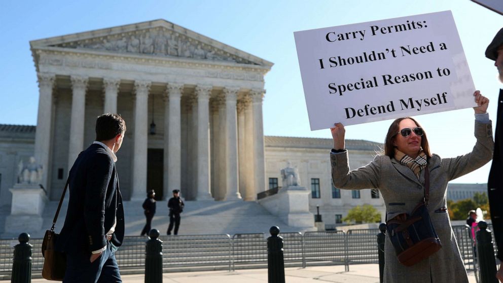 PHOTO: Katie Novotny walks along First Street while displaying a sign of protest during a demonstration at the U.S. Supreme Court in Washington, D.C., Nov. 3, 2021.