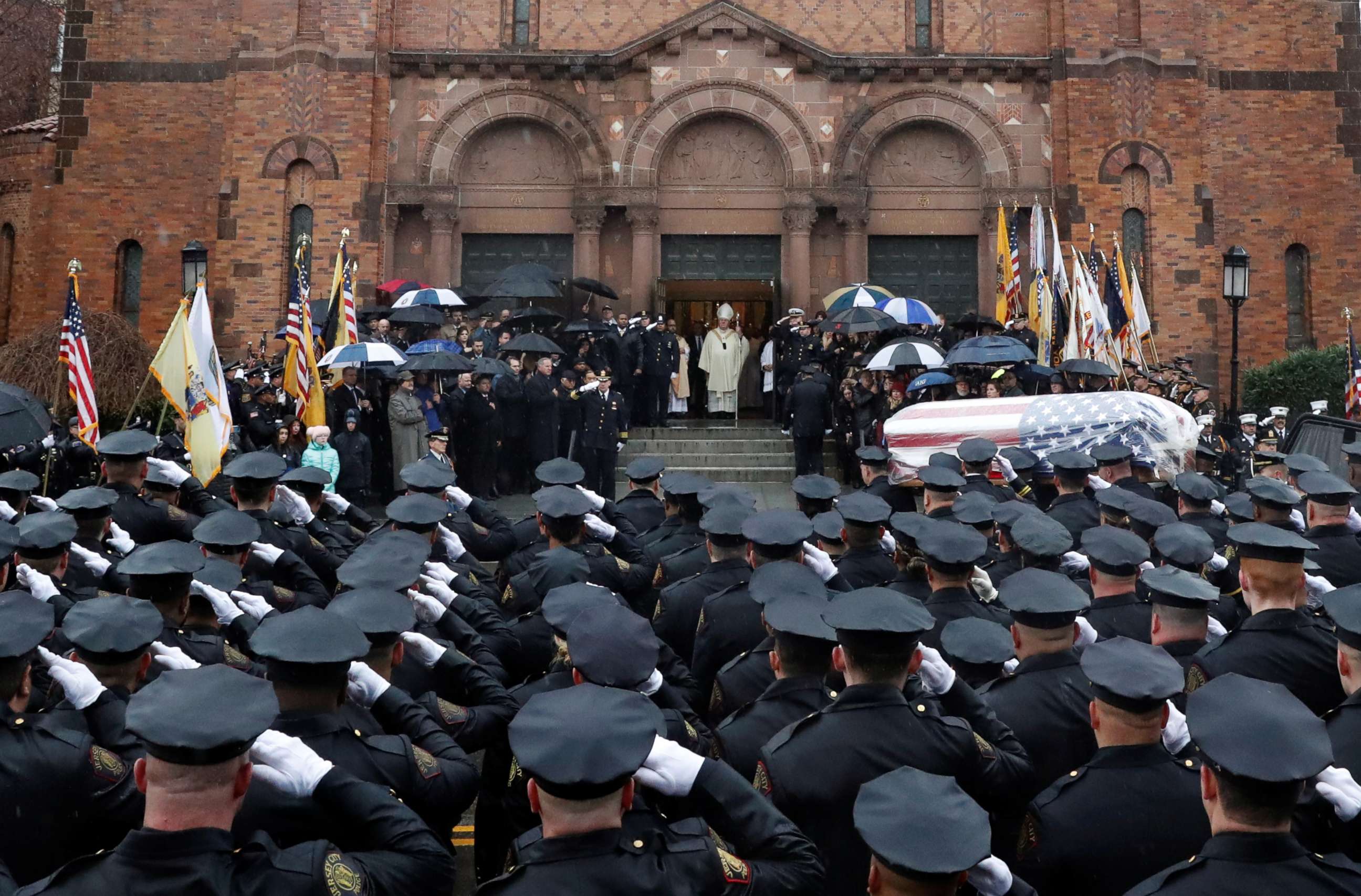 PHOTO: Police officers stand and salute as the casket is carried into the funeral service for Jersey City Police Detective Joseph Seals at St. Aedan's Church in Jersey City, N.J., Dec. 17, 2019.