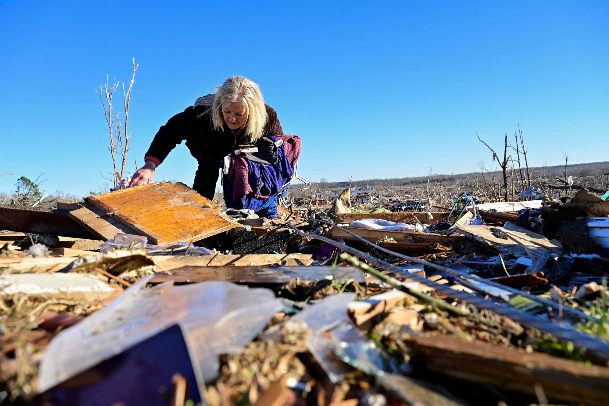 PHOTO: Laura Croft searches through debris near the location where her mother and aunt were found deceased after tornadoes ripped through several states, in downtown Dawson Springs, Ky., Dec. 13, 2021.