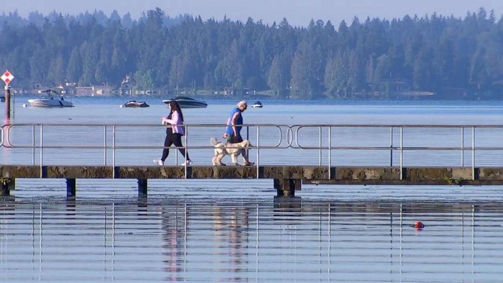 PHOTO: People walk along the water before the temperatures rise, July 26, 2022, in Seattle.
