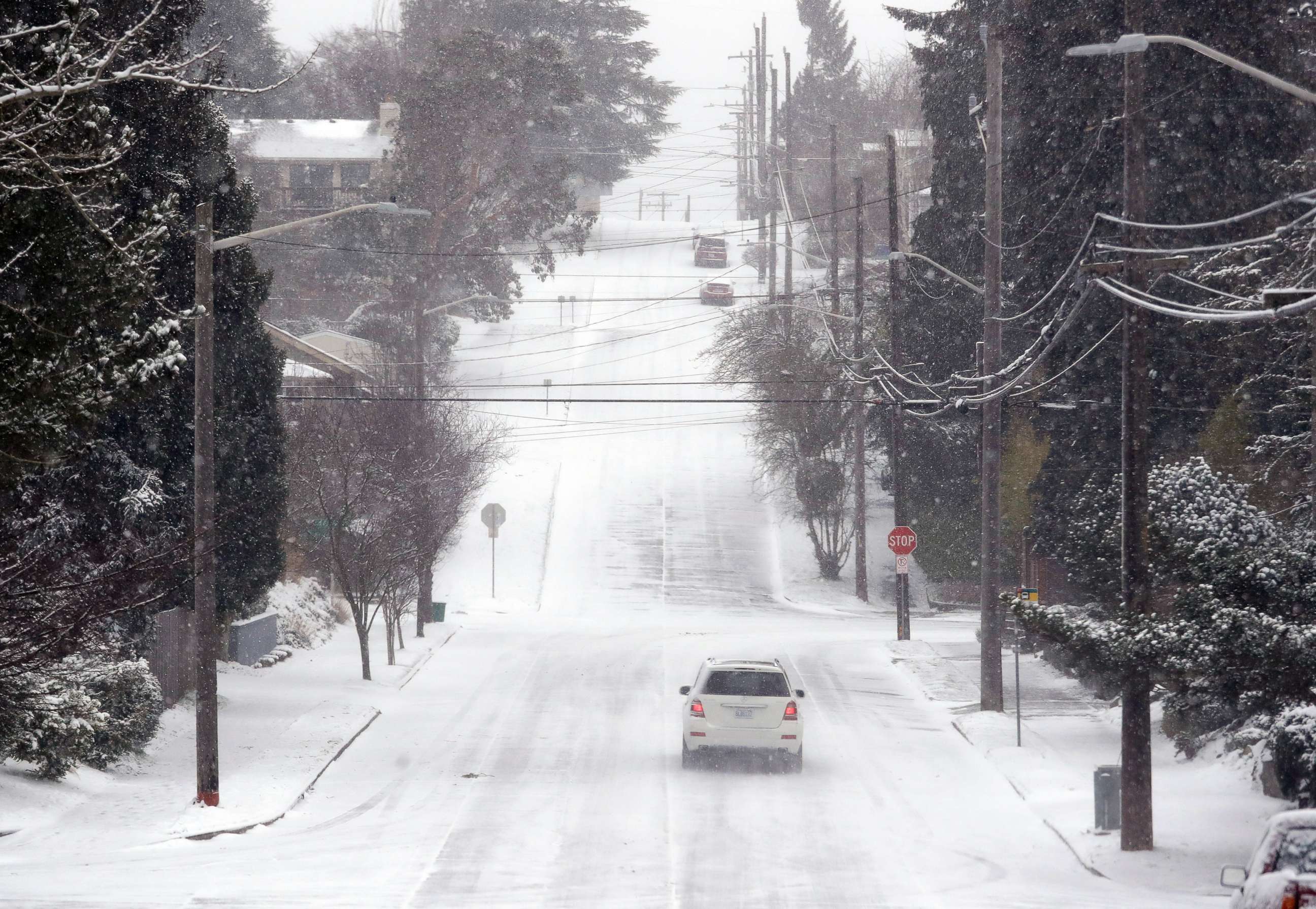 PHOTO: A lone car finds its way along an otherwise deserted street through snow and a cold wind Monday morning, Feb. 4, 2019, in Seattle.