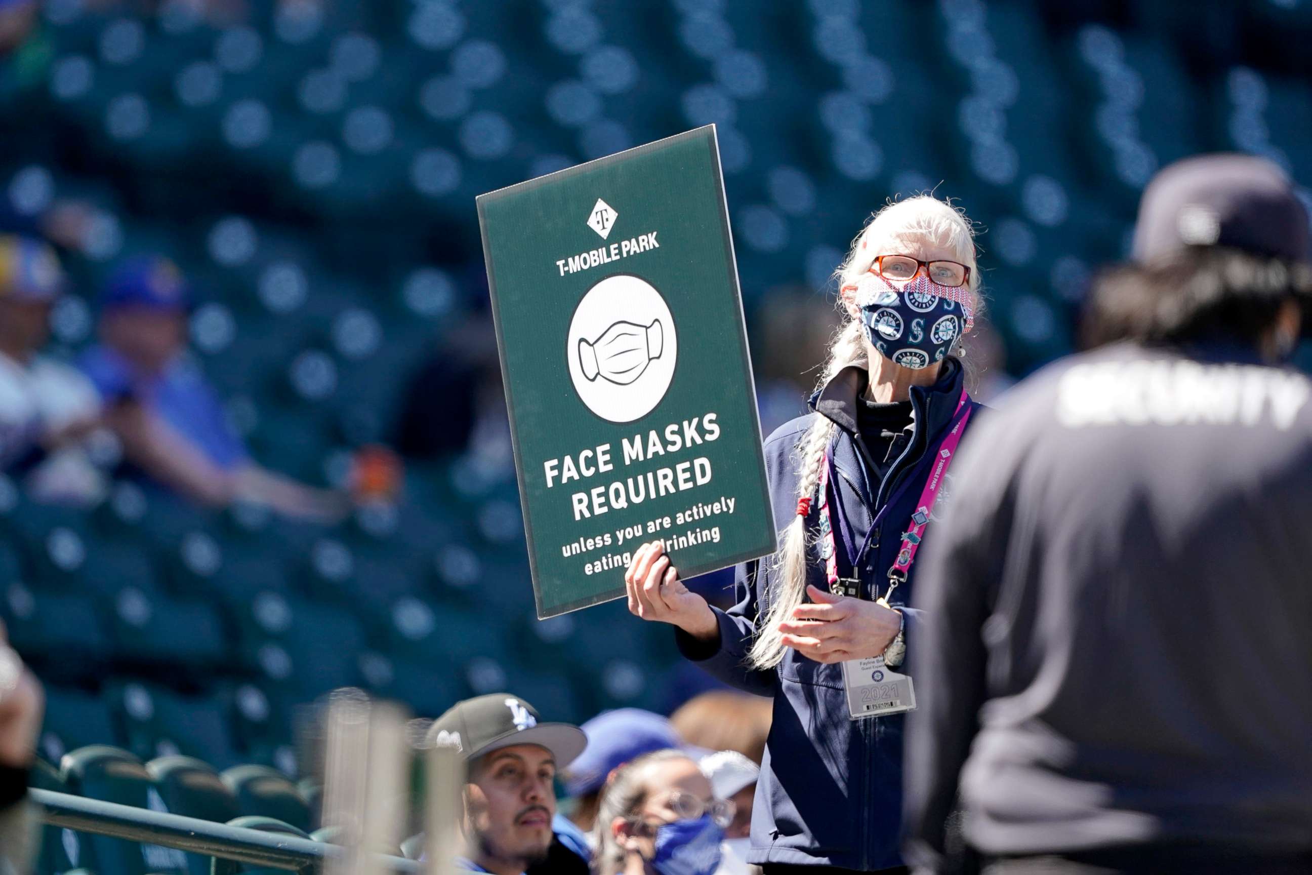 PHOTO: An usher holds up a sign reminding fans to wear face masks during a baseball game between the Seattle Mariners and the Los Angeles Dodgers, April 20, 2021, in Seattle.