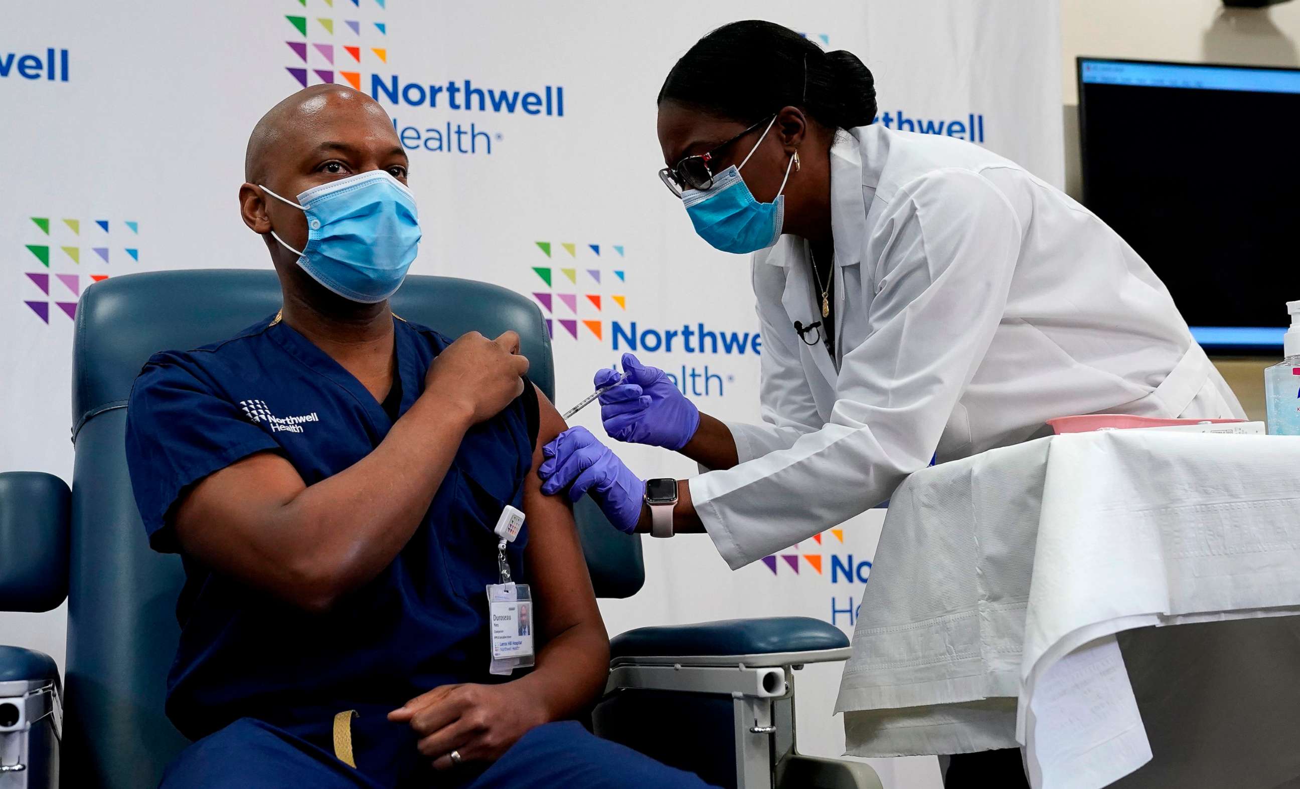 PHOTO: Members of the media watch as Dr. Yves Duroseau from Lennox Hill Hospital is inoculated with the Pfizer COVID-19 vaccine by Dr. Michelle Chester from Northwell Health at Long Island Jewish Medical Center, in New Hyde Park, N.Y. Dec.14, 2020.