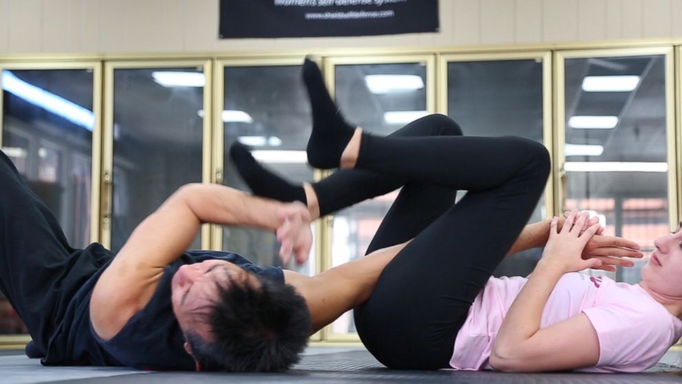 PHOTO: A woman demonstrates how to defend herself using her legs to trap her opponent's arm.